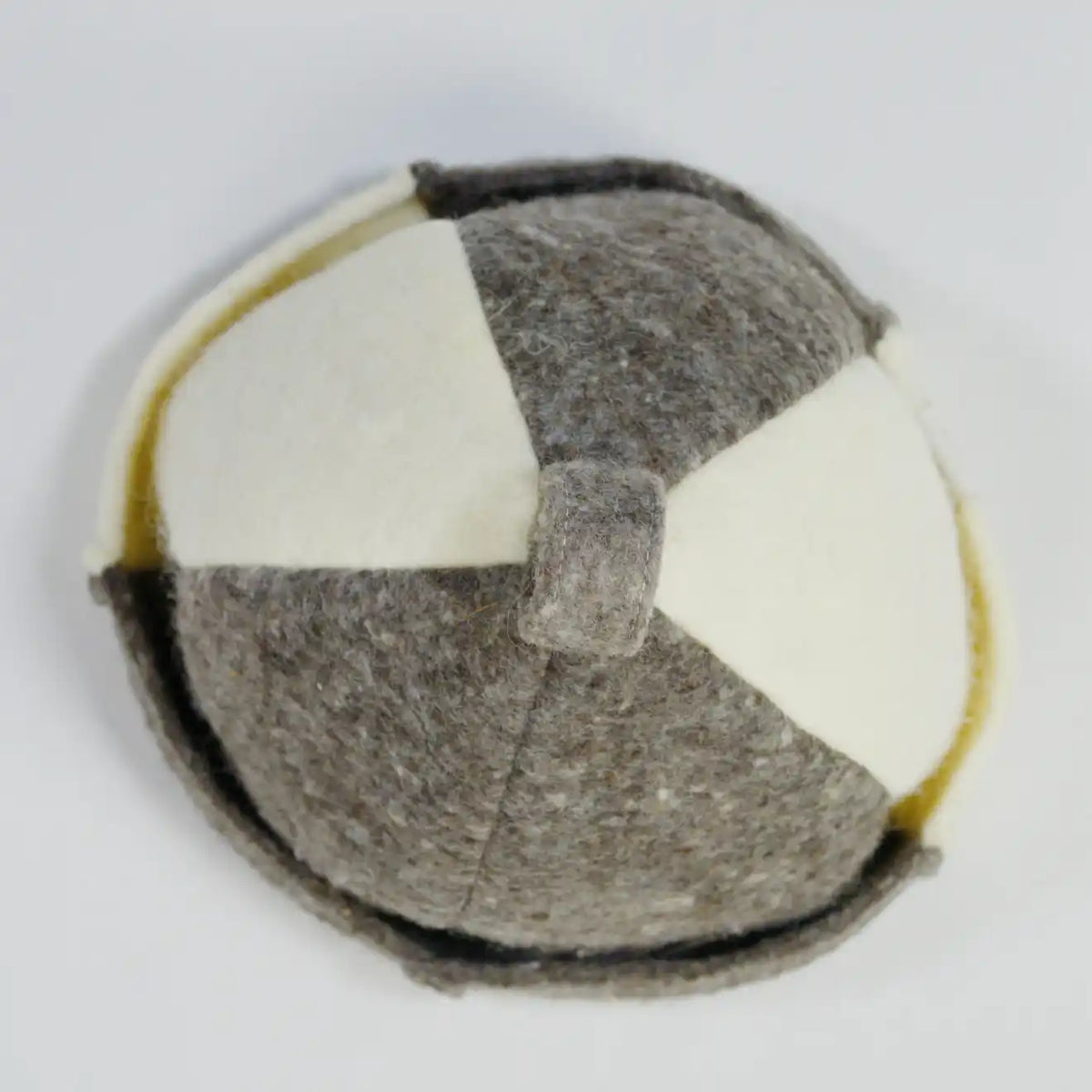 Top view of a handmade felt hat with a geometric patchwork design in gray and off-white, featuring a top loop and folded brim.